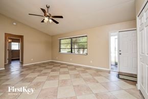 Cape Coral house for rent - an empty living room with a ceiling fan and a window