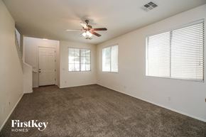 Gilbert house for rent - A spacious room with a ceiling fan and carpeted floor.