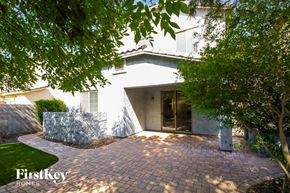 Gilbert house for rent - A white house with a brick patio and trees in the foreground.