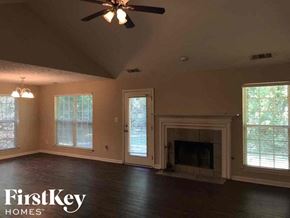Gainesville house for rent - an empty living room with a fireplace and a ceiling fan