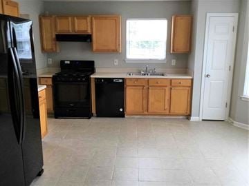 Douglasville house for rent - a kitchen with black appliances and wooden cabinets