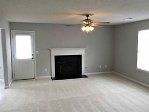 Douglasville house for rent - an empty living room with a fireplace and a ceiling fan