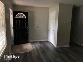 Richton Park house for rent - A black door with a white arch above it is in a room with wooden floors.