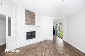 Fort Worth house for rent - A spacious room with a fireplace and wooden flooring.