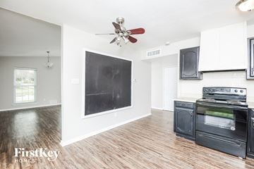 Fort Worth house for rent - A kitchen with a black fridge and stove top oven.