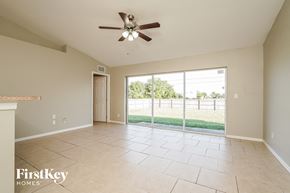 Lehigh Acres house for rent - A spacious room with a ceiling fan and sliding glass doors leading to a backyard.