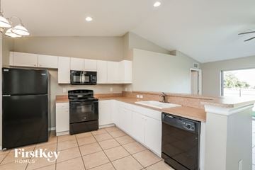 Lehigh Acres house for rent - A kitchen with black appliances and white cabinets.