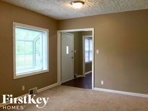 Indianapolis house for rent - an empty living room with a large window and a door to a hallway