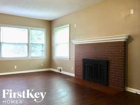 Indianapolis house for rent - a living room with a brick fireplace and wooden floors