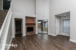 Mesquite house for rent - an empty living room with a brick fireplace and wooden floors