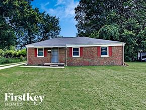 Indianapolis house for rent - A brick house with a porch and a tree in the background.