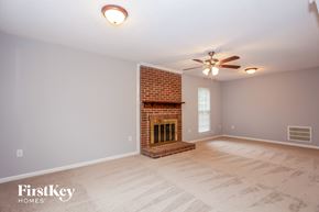 Charlotte house for rent - A room with a brick fireplace and a ceiling fan.