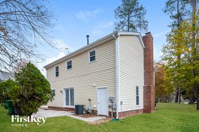 Charlotte house for rent - A house with a white door and a chimney is surrounded by trees.