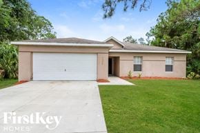 North Port house for rent - a beige house with a white garage door and a lawn
