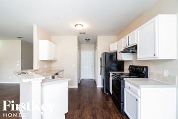 North Port house for rent - a kitchen with white cabinets and a black stove and refrigerator