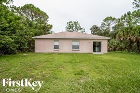 North Port house for rent - a small pink house in a grassy yard with trees
