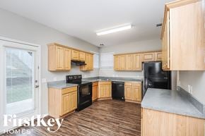 Fort Worth house for rent - an empty kitchen with wooden cabinets and black appliances