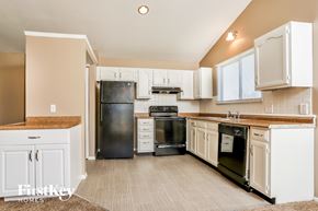 Florissant house for rent - a kitchen with white cabinets and black appliances