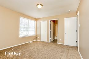 Florissant house for rent - a master bedroom with carpet and a door to a closet and a window