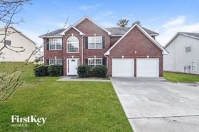 Douglasville house for rent - a red brick house with a white garage door and a green lawn