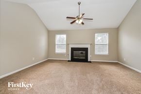 Douglasville house for rent - a living room with a fireplace and a ceiling fan