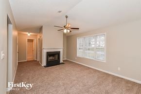 Douglasville house for rent - an empty living room with a fireplace and a ceiling fan