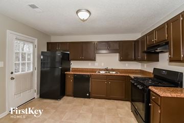 Douglasville house for rent - a kitchen with black appliances and brown cabinets
