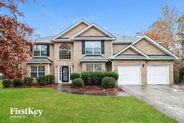 Powder Springs house for rent - a brick house with two garage doors and a lawn