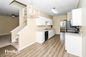 Union City house for rent - a kitchen with white cabinets and black appliances and a chandelier