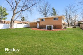 Matteson house for rent - A house with a brown and beige exterior is surrounded by a green lawn.
