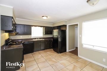 Memphis house for rent - a kitchen with black cabinets and a sink and a refrigerator
