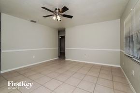Lehigh Acres house for rent - an empty living room with a ceiling fan and tiled floors