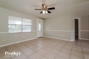 Lehigh Acres house for rent - an empty living room with a ceiling fan and tiled floor