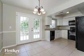 Lehigh Acres house for rent - a kitchen with white cabinets and a door to a patio