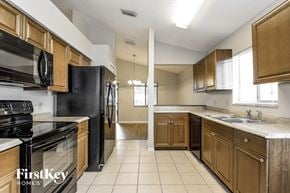 Plant City house for rent - a kitchen with wooden cabinets and black appliances
