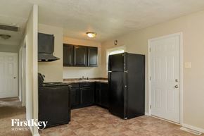 Indianapolis house for rent - a kitchen with black appliances and a white door