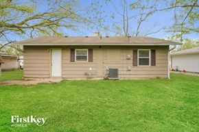 Indianapolis house for rent - a small tan house with a grassy yard and a tree