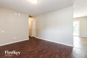 Indianapolis house for rent - A room with wooden floors and white walls, with a door leading to another room.