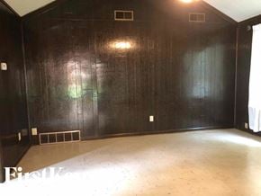 Memphis house for rent - an empty room with black walls and a wooden floor