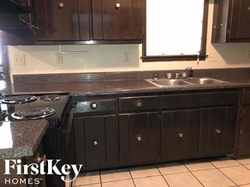 Memphis house for rent - a kitchen with dark wood cabinets and a sink