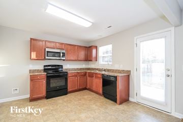 Winston-Salem house for rent - a kitchen with wood cabinets and black appliances and a window