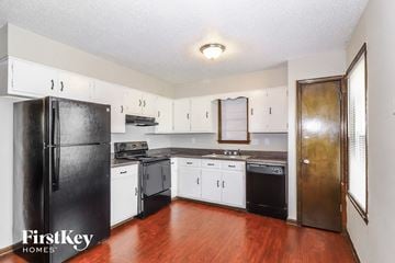 Memphis house for rent - A kitchen with a black fridge and wooden floors.