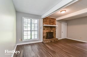 Memphis house for rent - an empty living room with a stone fireplace and wooden floors