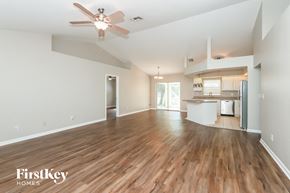 Cape Coral house for rent - an empty living room with a ceiling fan and a kitchen