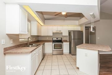 Cape Coral house for rent - a kitchen with white cabinets and stainless steel appliances