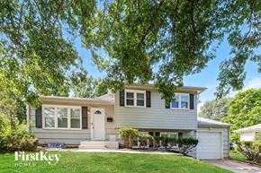 Kansas City house for rent - a white and gray house with a lawn and trees
