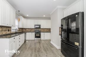 Winston-Salem house for rent - a renovated kitchen with white cabinets and black appliances
