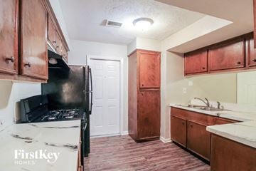 Houston house for rent - a kitchen with wooden cabinets and a black stove and refrigerator