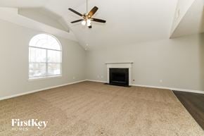 Douglasville house for rent - an empty living room with a fireplace and a ceiling fan