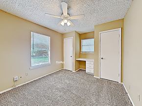 Fort Worth house for rent - an empty bedroom with a ceiling fan and a desk